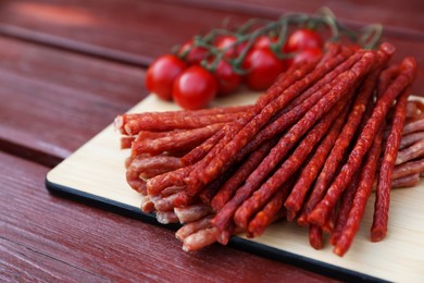Photo of Tasty dry cured sausages (kabanosy) on wooden table, closeup