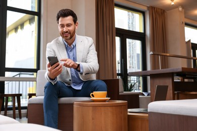 Handsome man using his smartphone in cafe