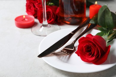 Photo of Beautiful place setting with dishware, candles and rose for romantic dinner on light table