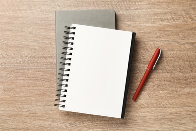 Notebooks and pen on wooden table, flat lay