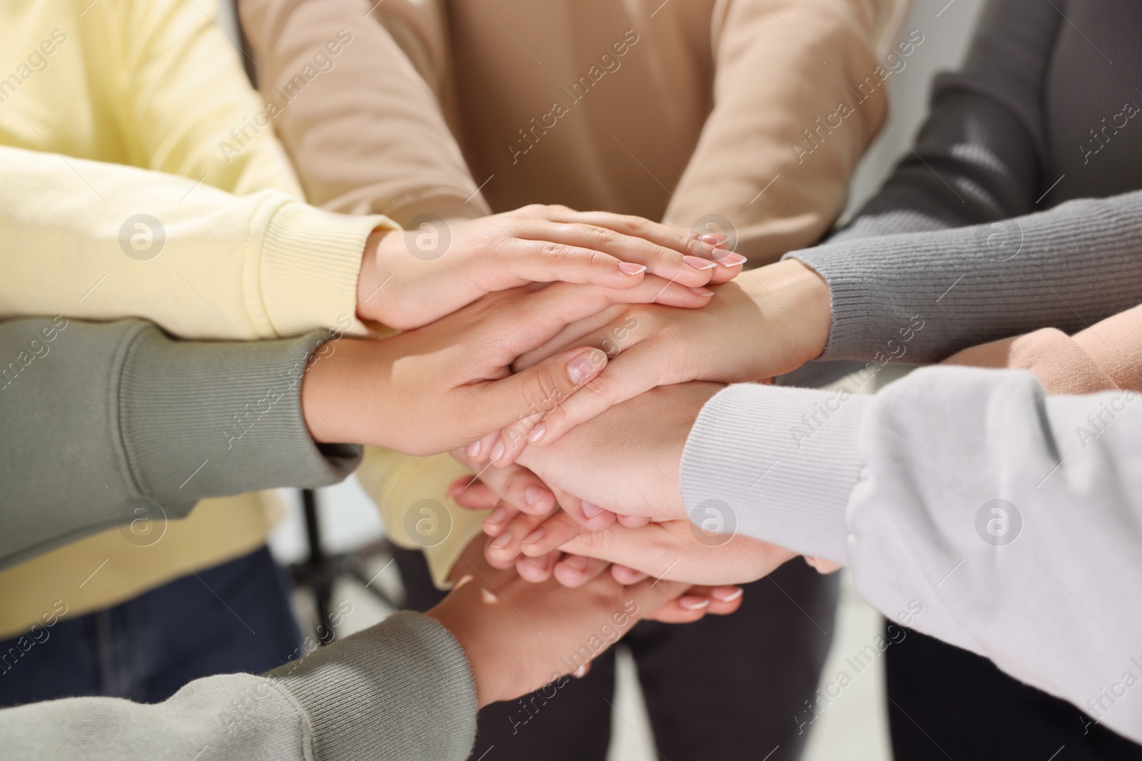 Photo of Group of people holding hands together indoors, closeup. Unity concept