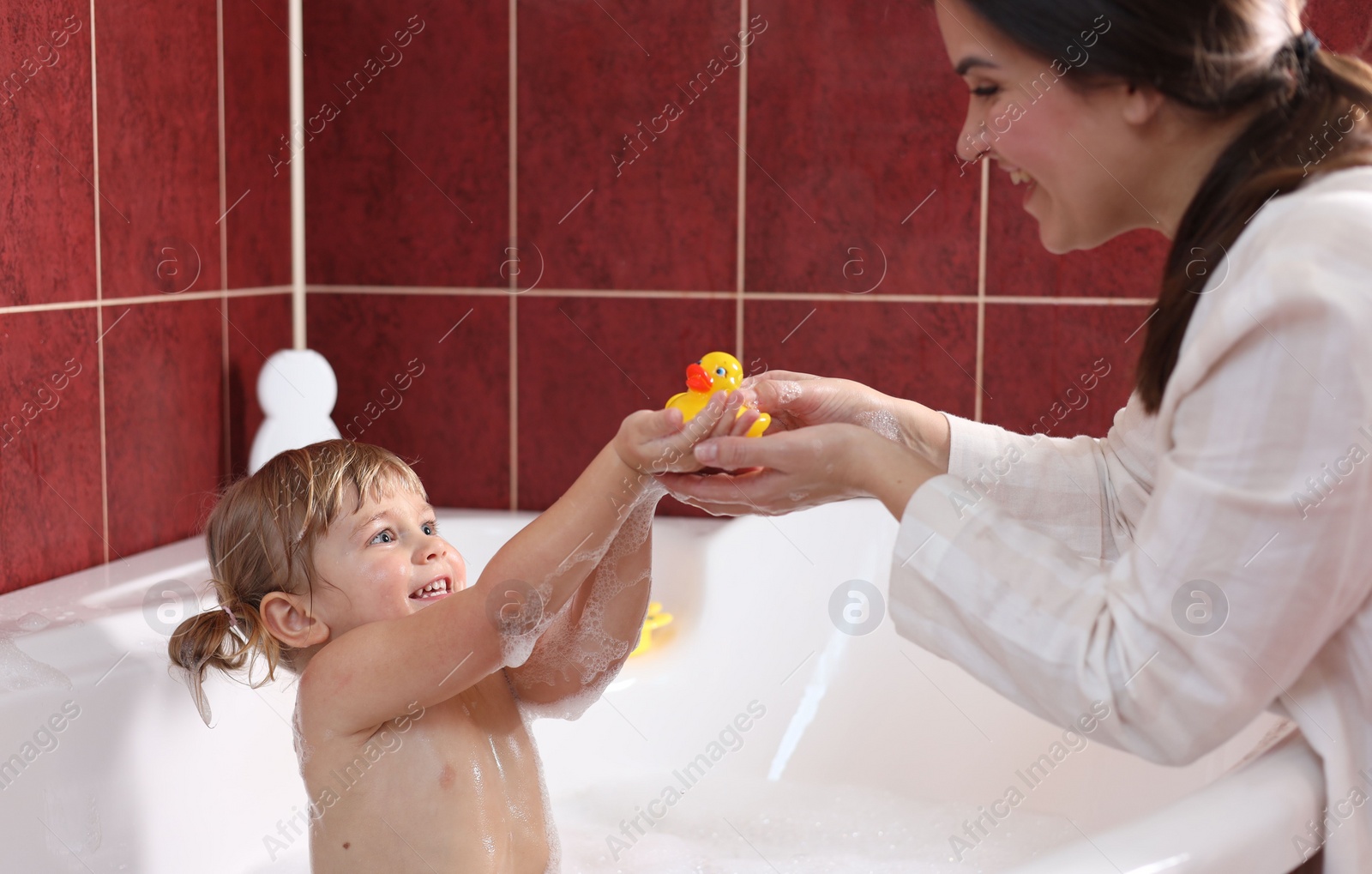 Photo of Happy mother playing with her little daughter in bathroom