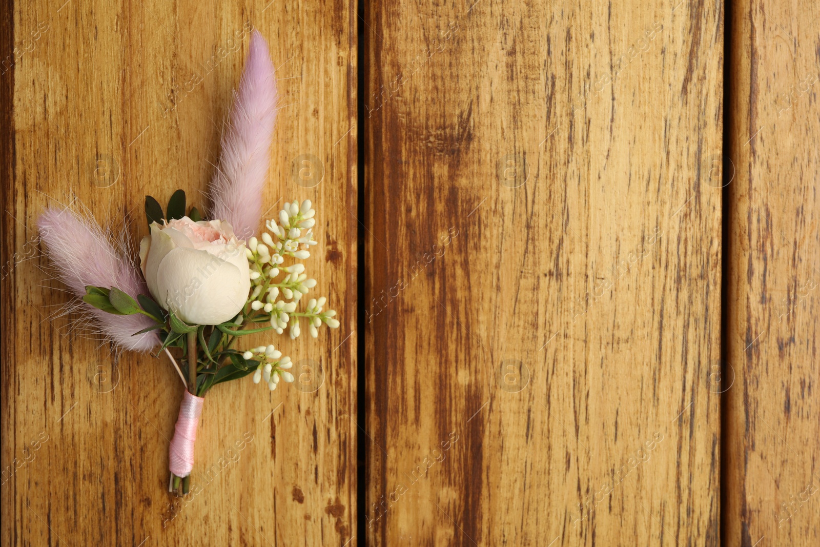Photo of Small stylish boutonniere on wooden table, top view. Space for text