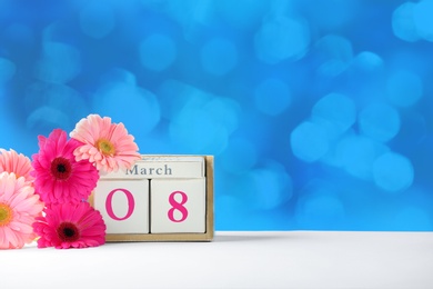 Photo of Calendar and flowers on table against color background, space for text. International Women's Day