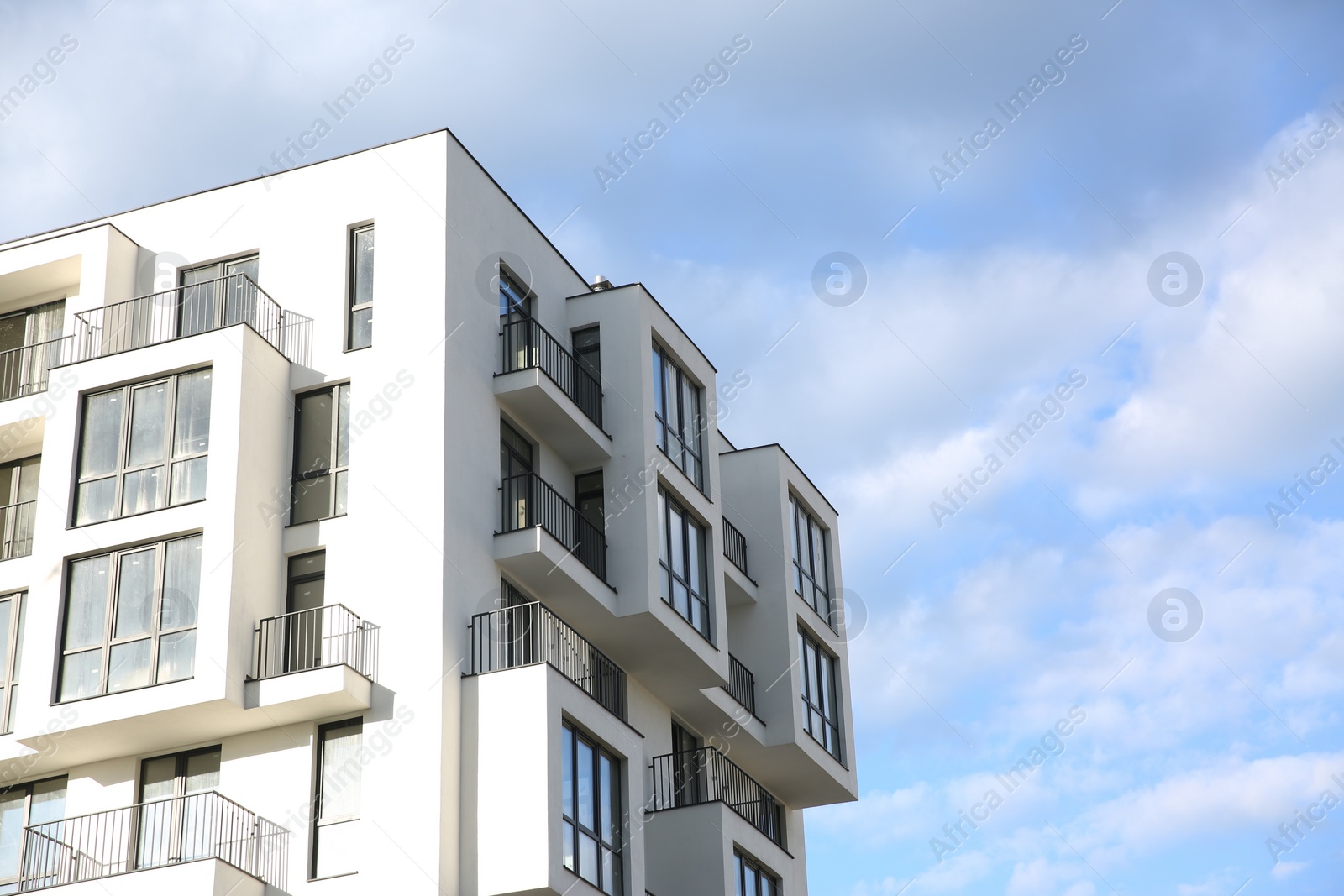 Photo of Modern building with big windows against blue sky outdoors, space for text