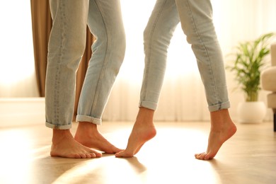 Couple dancing barefoot at home, closeup. Floor heating system