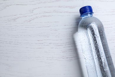 Plastic bottle with water on white wooden background, top view. Space for text