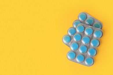 Photo of Blisters with cough drops on yellow background, flat lay. Space for text