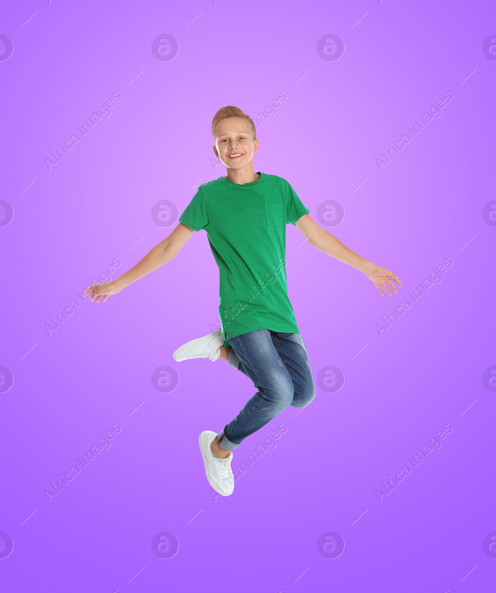 Image of Happy boy jumping on color gradient background