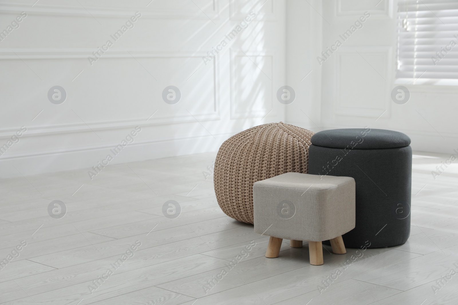 Photo of Different stylish pouf and ottomans in room, space for text