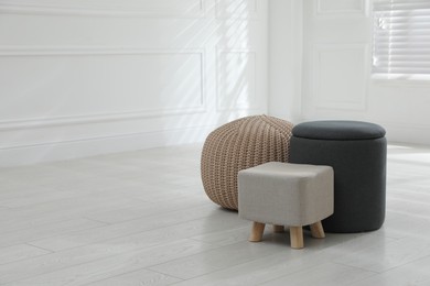 Photo of Different stylish pouf and ottomans in room, space for text