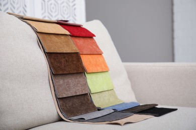 Photo of Catalog of colorful fabric samples on beige sofa indoors
