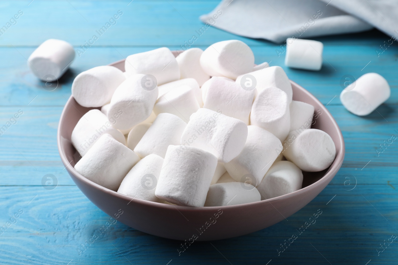 Photo of Delicious puffy marshmallows on light blue wooden table, closeup
