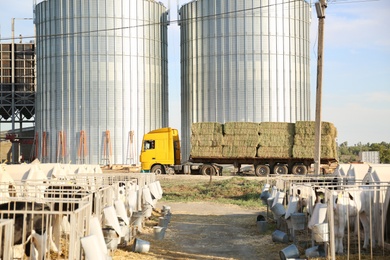 Photo of Stainless steel milk silos and truck with hay bales on farm. Animal husbandry