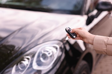 Woman holding car flip key near her vehicle outdoors, closeup