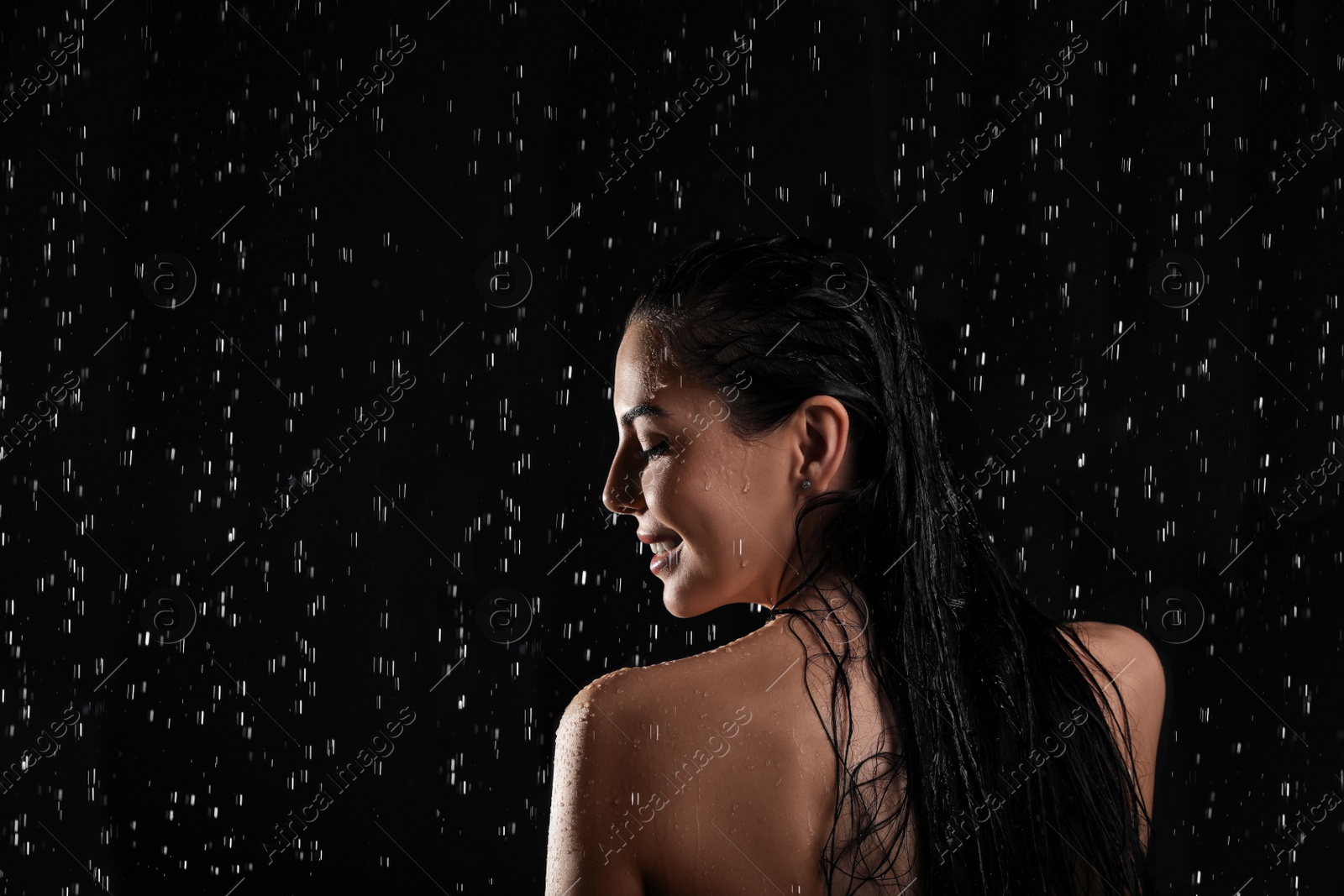 Photo of Pretty woman taking shower on black background. Washing hair