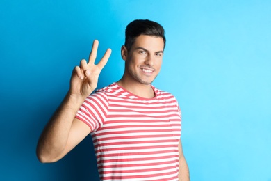Photo of Man showing number two with his hand on light blue background