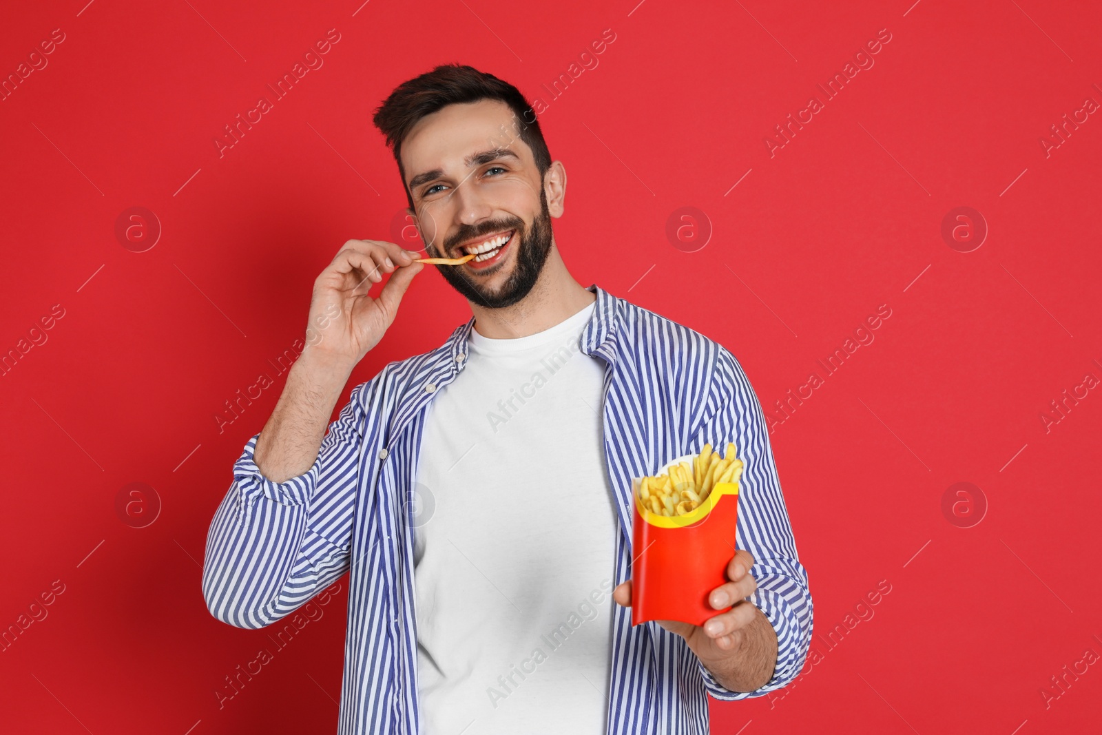 Photo of Man eating French fries on red background