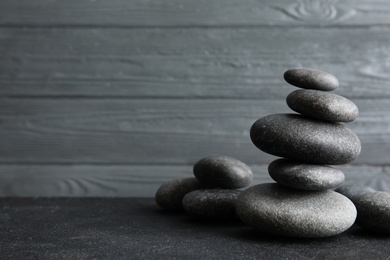 Photo of Stacked zen stones on table against wooden background. Space for text