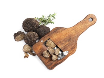 Photo of Wooden slicer with black truffles and thyme on white background, top view