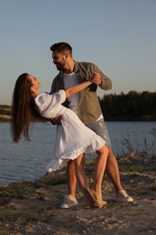 Photo of Beautiful couple dancing near river at sunset