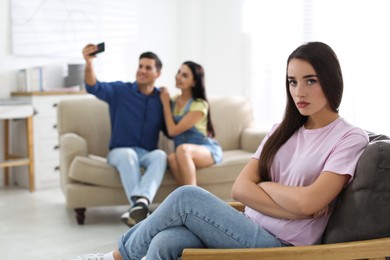 Unhappy woman feeling jealous while couple spending time together at home