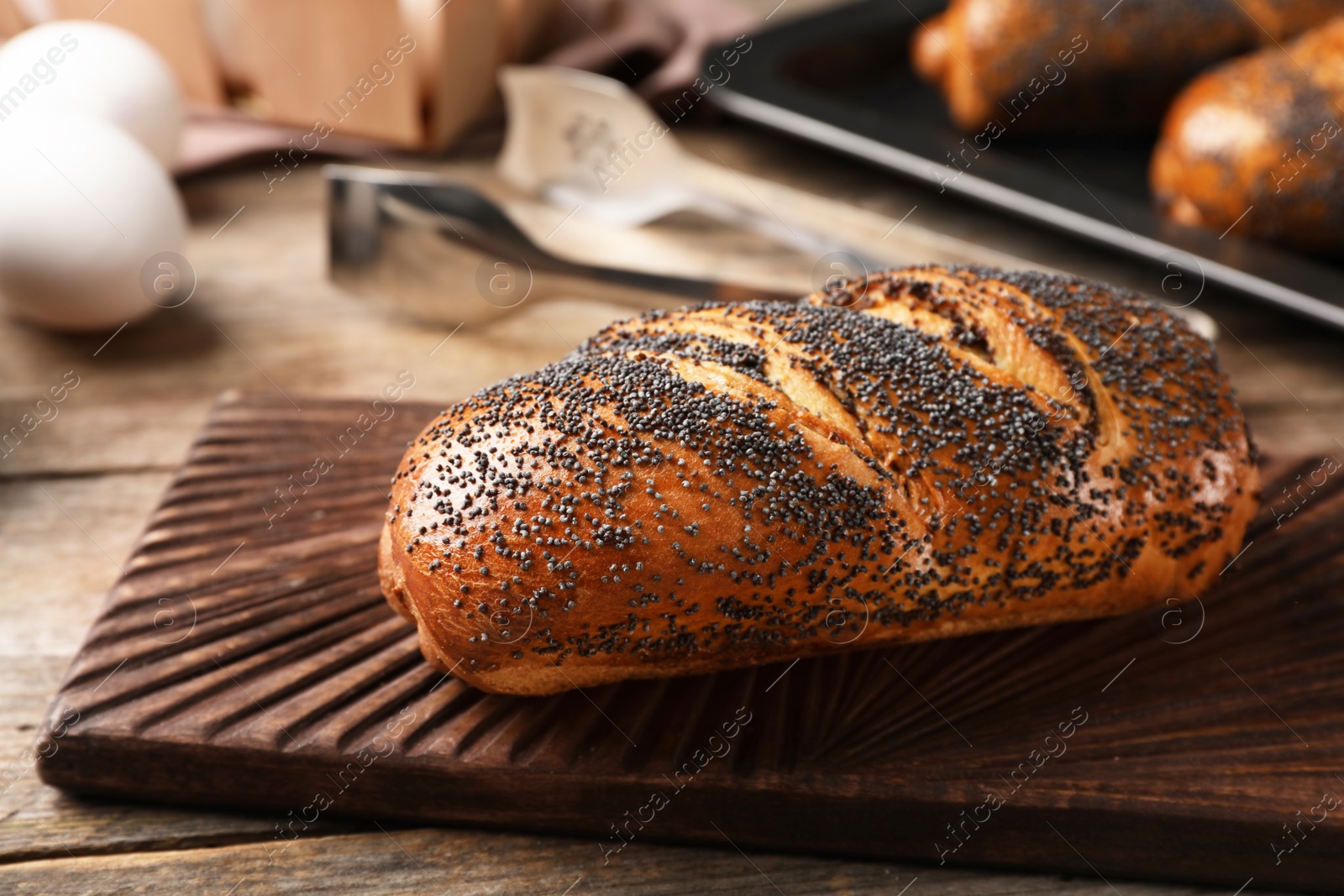 Photo of Board with freshly baked poppy seed roll on table