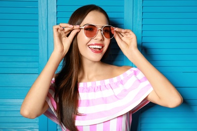 Beautiful woman in red sunglasses near blue wooden folding screen