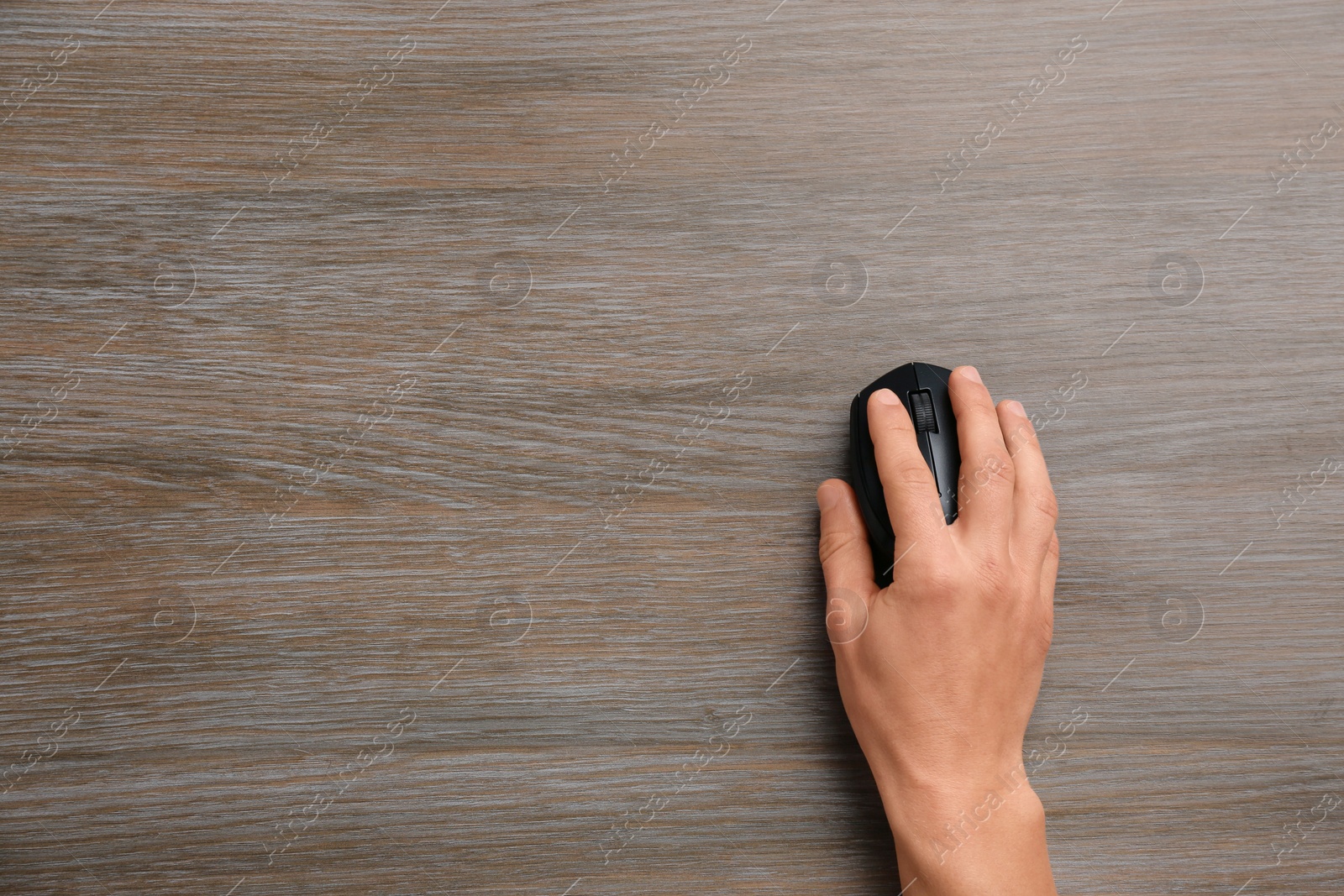 Photo of Man using computer mouse on wooden table, top view. Space for text