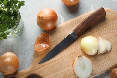 Photo of Whole and cut onion on grey textured table, flat lay