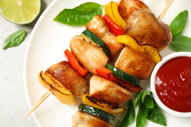 Photo of Delicious chicken shish kebabs with vegetables and ketchup on grey table, top view
