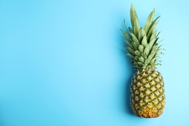 Fresh ripe juicy pineapple on light blue background, top view. Space for text