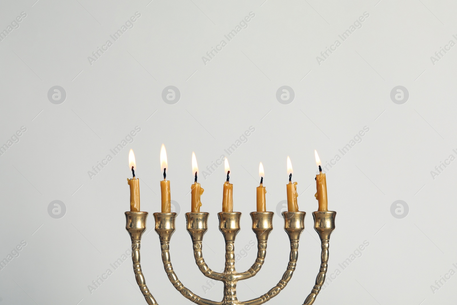 Photo of Golden menorah with burning candles on light grey background, space for text