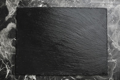 Black textured slate board on marble background