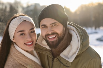 Beautiful happy couple in snowy park on winter day