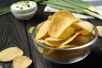 Photo of Bowl with potato chips on wooden table, closeup. Space for text