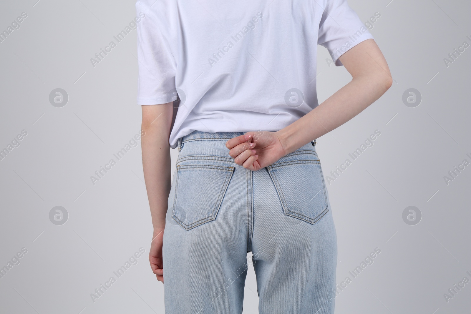 Photo of SOS gesture. Woman showing signal for help on light grey background, back view