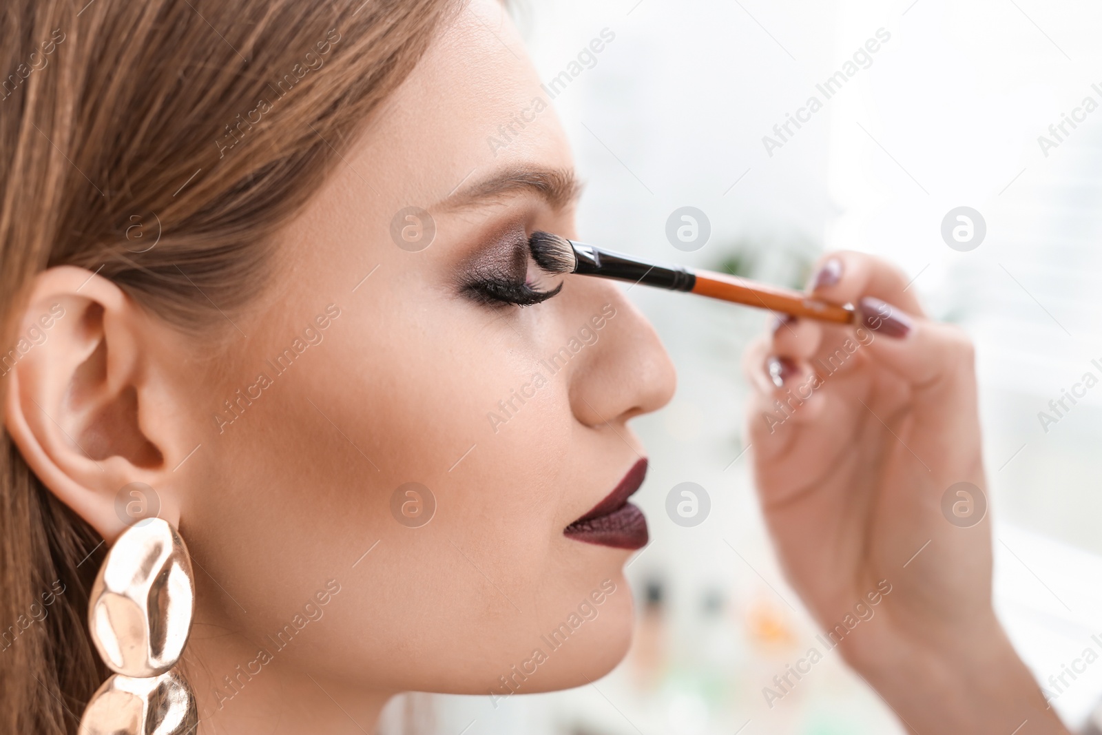 Photo of Professional makeup artist working with beautiful young woman in studio