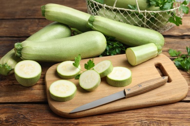 Photo of Cut and whole ripe zucchinis on wooden table