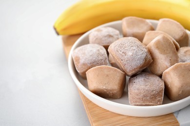 Photo of Frozen banana puree cubes and ingredient on light grey table, closeup. Space for text