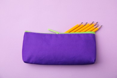 Photo of Many sharp pencils in pencil case on pink background, top view