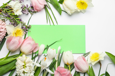 Photo of Fresh spring flowers and blank card on white background, top view. Space for text