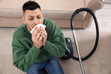 Photo of Man with vacuum cleaner suffering from dust allergy at home, above view