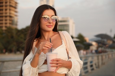 Photo of Beautiful young woman with tasty milk shake outdoors