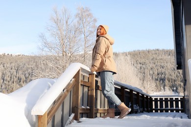 Photo of Happy young woman on terrace outdoors. Winter vacation