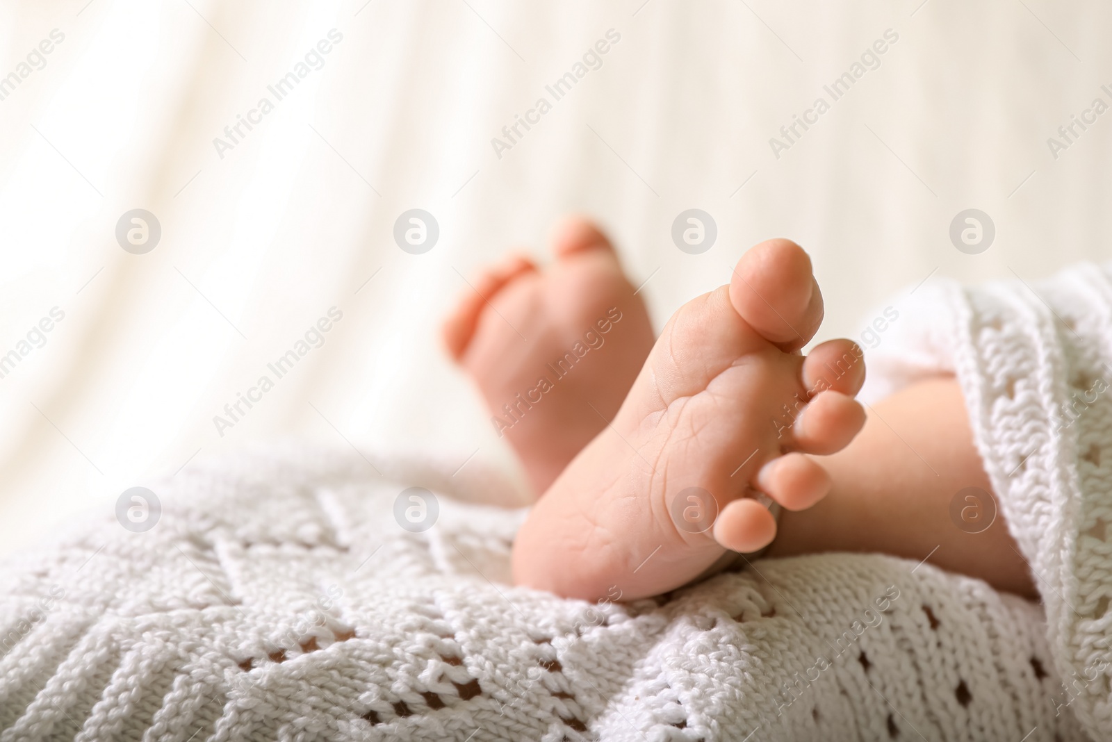 Photo of Cute newborn baby lying on white knitted plaid, closeup of legs. Space for text