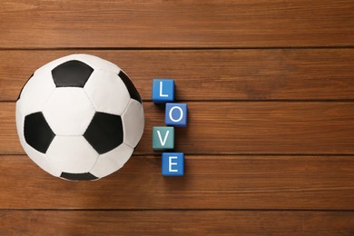 Photo of Soccer ball and cubes with word Love on wooden background, flat lay. Space for text