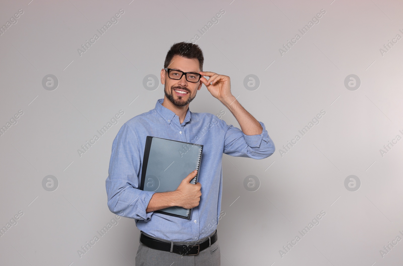 Photo of Happy teacher with glasses and stationery against beige background