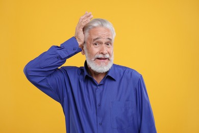 Photo of Portrait of embarrassed senior man on orange background