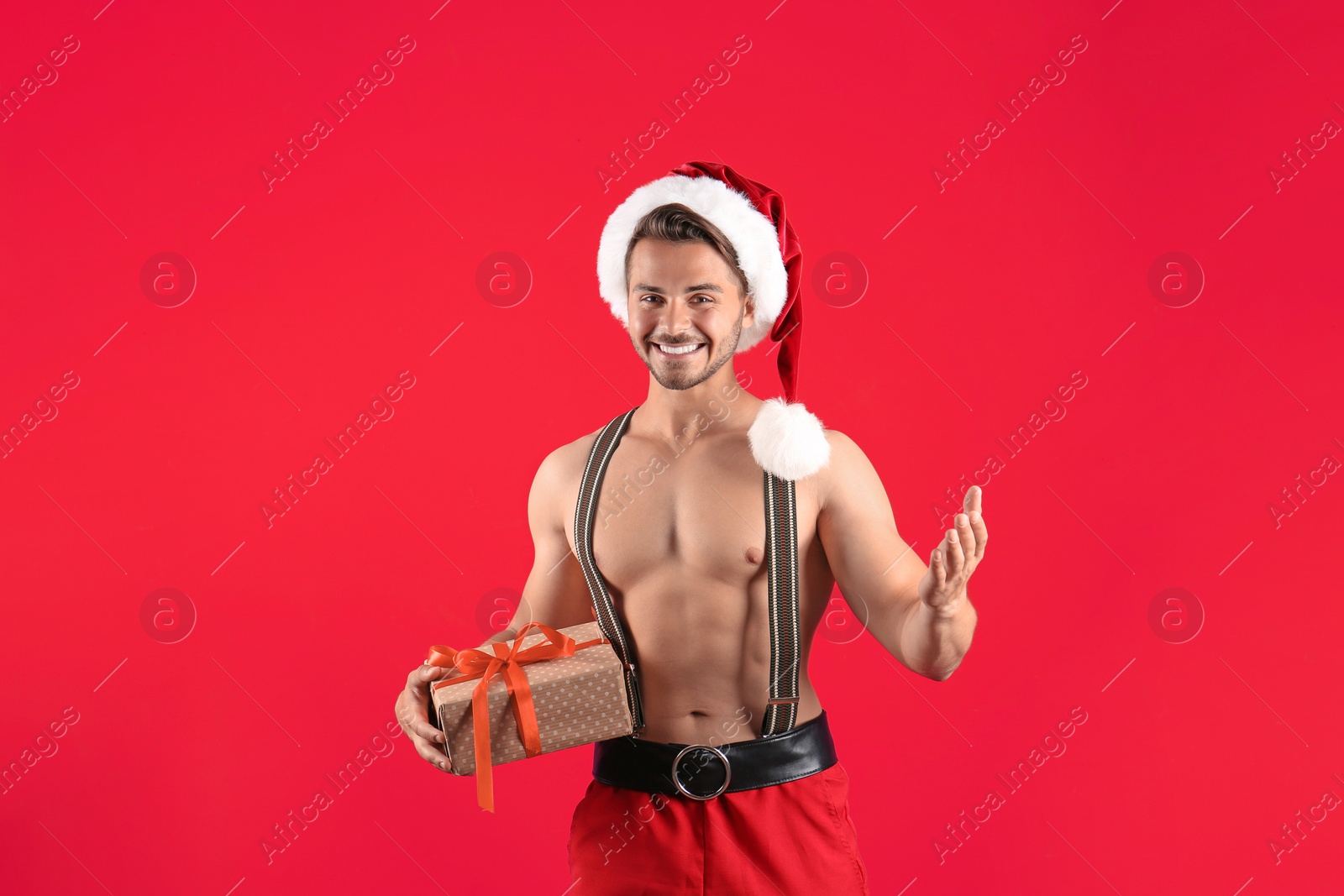 Photo of Shirtless sexy young Santa Claus with gift on color background